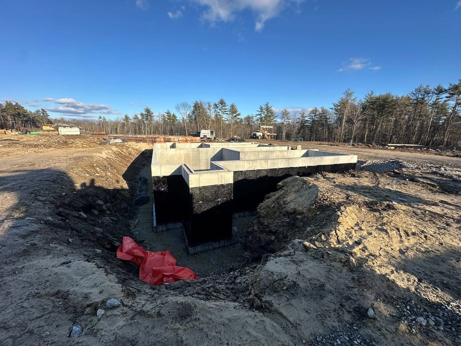 Foundation walls with black sealant in a large dirt excavation area