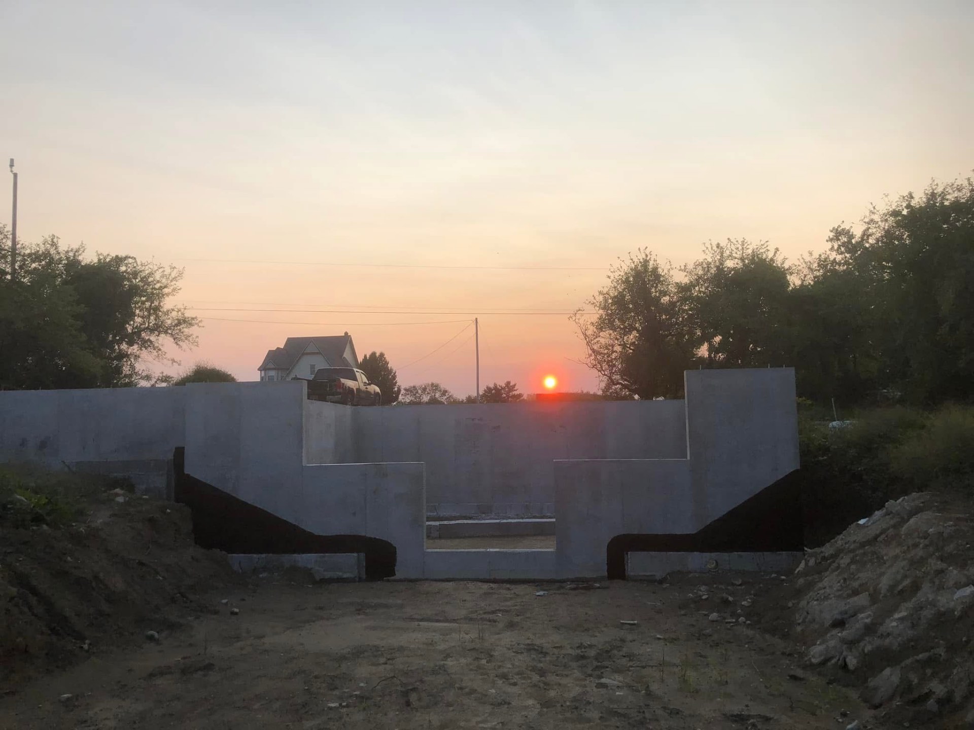 Completed foundation sealed with black waterproofing at sunset