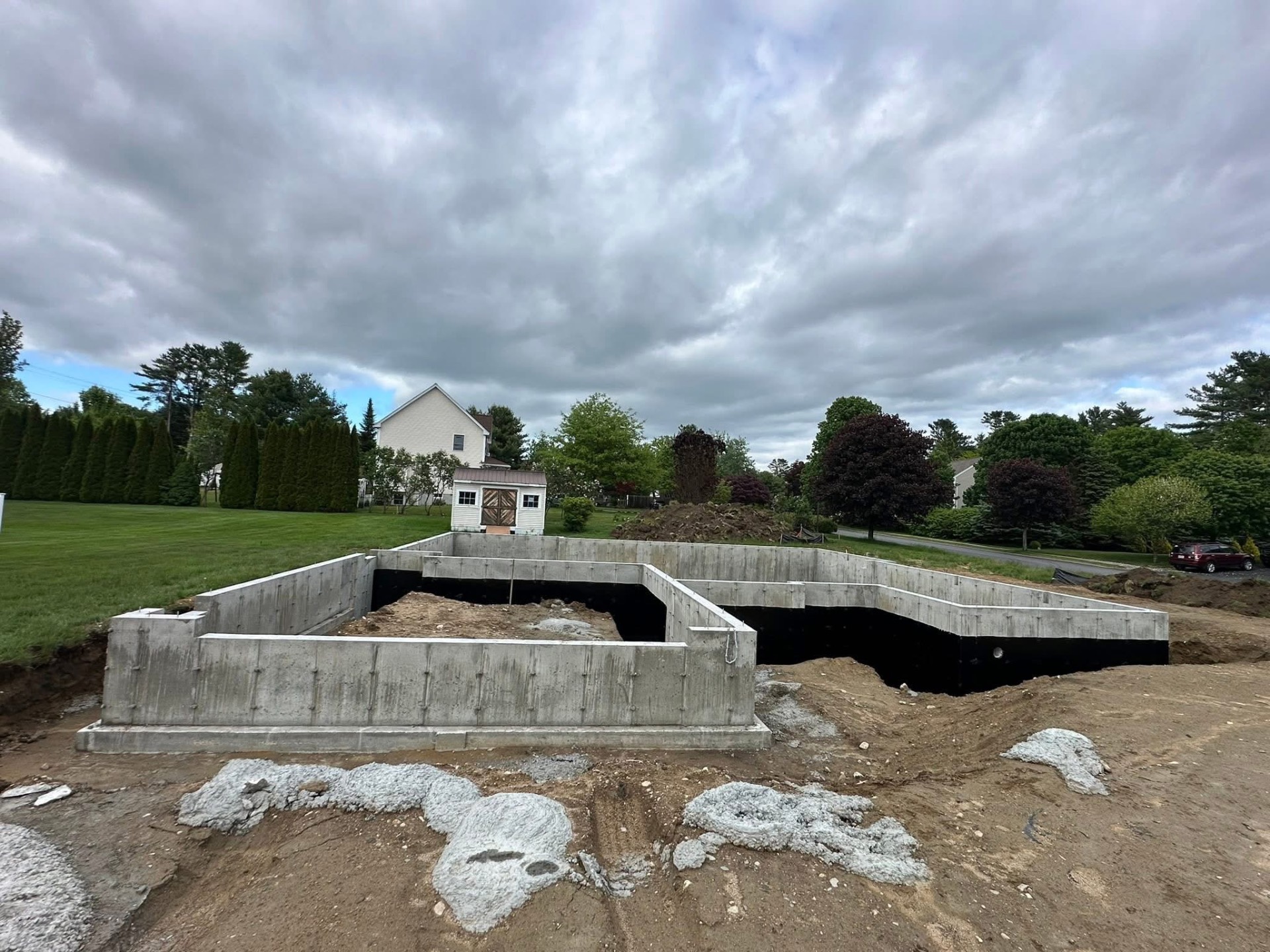 Residential foundation with black waterproofing complete in a Maine neighborhood