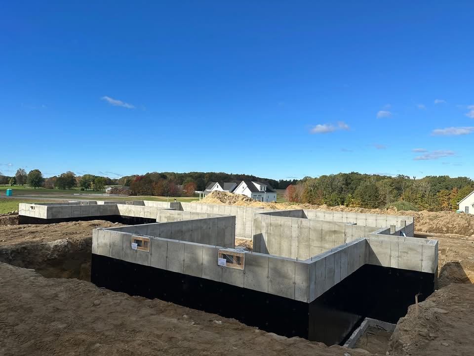 Multiple poured foundations with black waterproof coating on an open lot